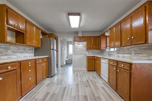 kitchen featuring light hardwood / wood-style flooring, decorative backsplash, sink, white dishwasher, and stainless steel fridge