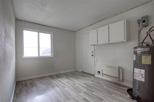 clothes washing area featuring water heater, cabinets, and light wood-type flooring