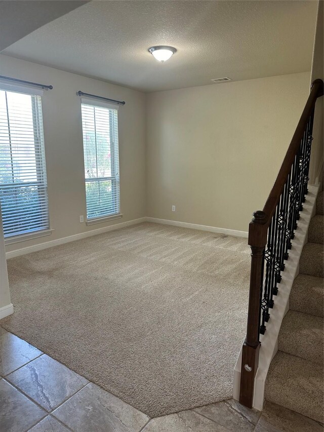 carpeted spare room with a textured ceiling