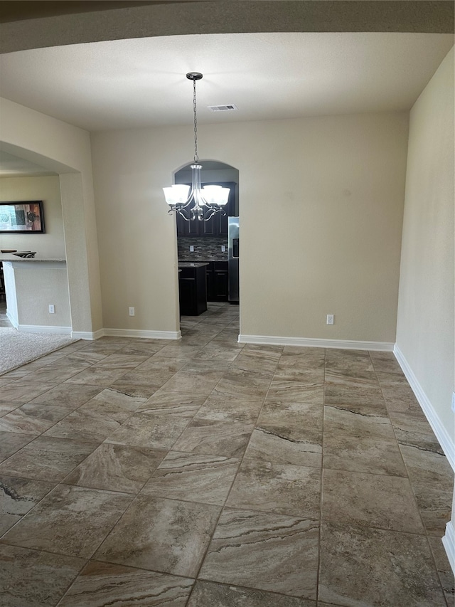 unfurnished dining area featuring an inviting chandelier and tile patterned floors