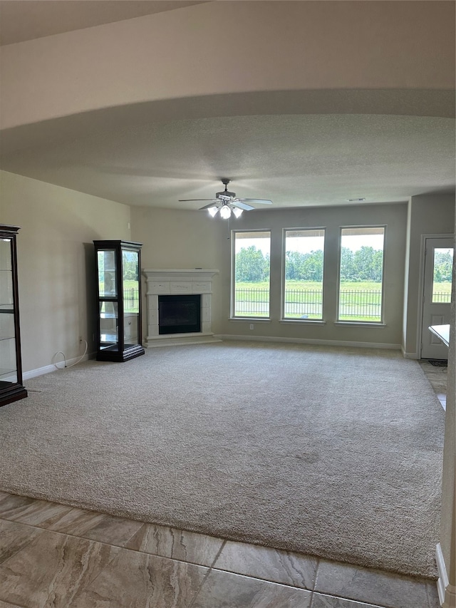 unfurnished living room with ceiling fan, light colored carpet, and a textured ceiling