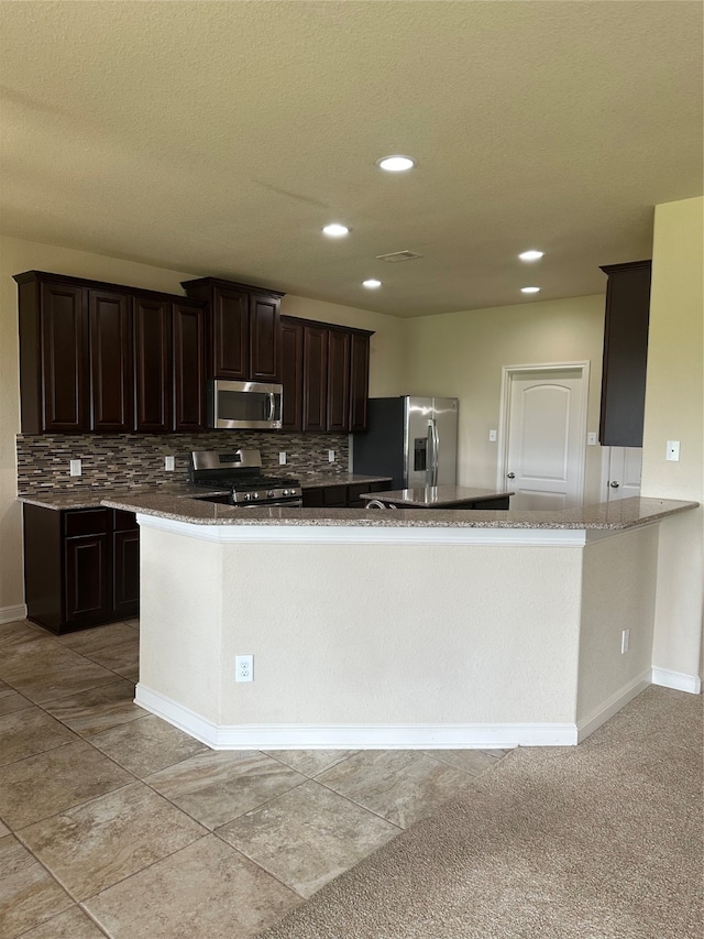 kitchen with tasteful backsplash, light tile patterned floors, stainless steel appliances, kitchen peninsula, and dark brown cabinets