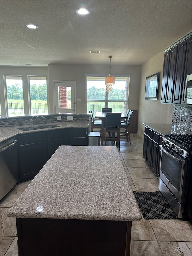 kitchen with a center island, sink, appliances with stainless steel finishes, and light stone countertops