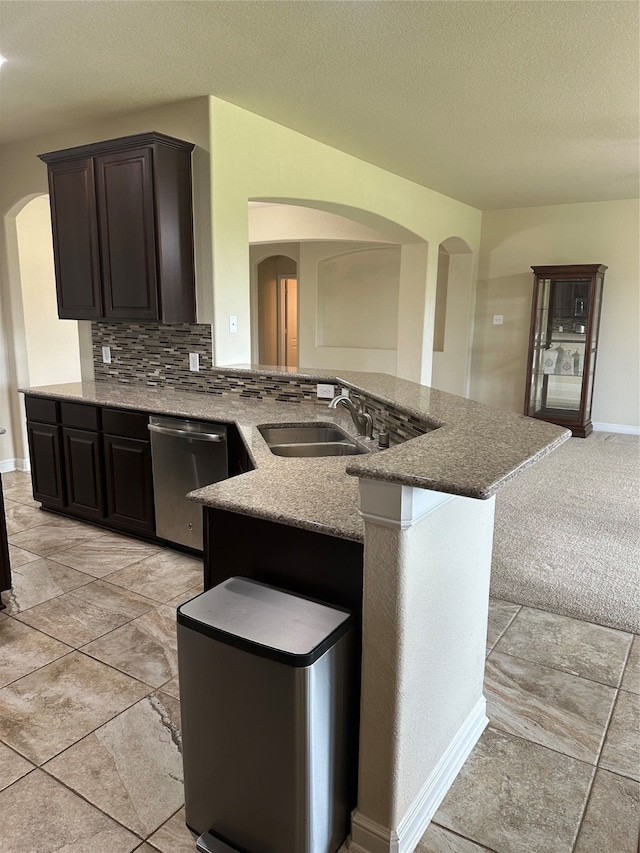 kitchen with light tile patterned flooring, backsplash, sink, stainless steel dishwasher, and stone countertops