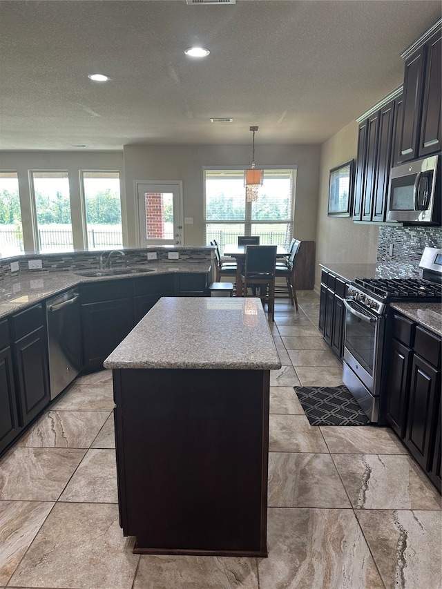 kitchen featuring appliances with stainless steel finishes, a kitchen island, a wealth of natural light, and backsplash