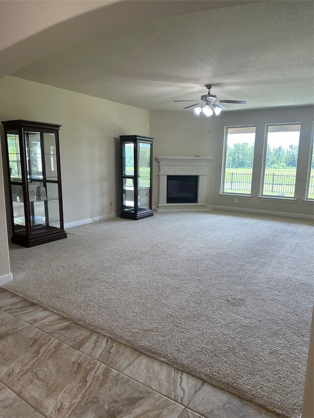 unfurnished living room featuring ceiling fan, light carpet, and a textured ceiling