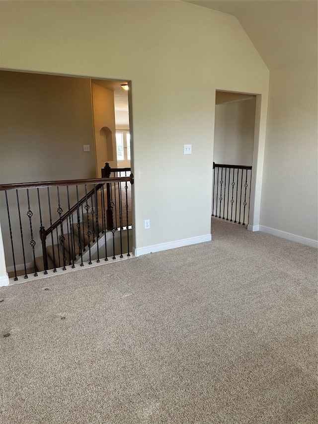 carpeted empty room featuring lofted ceiling