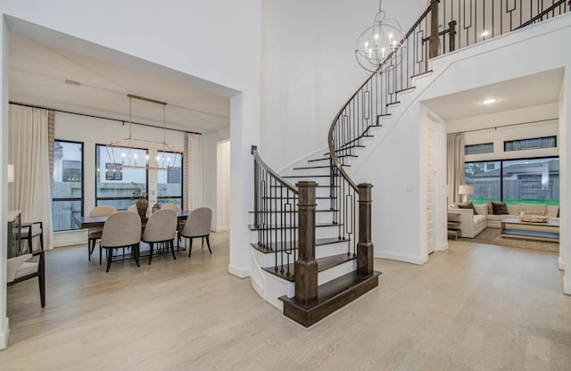 stairs with hardwood / wood-style flooring and a notable chandelier