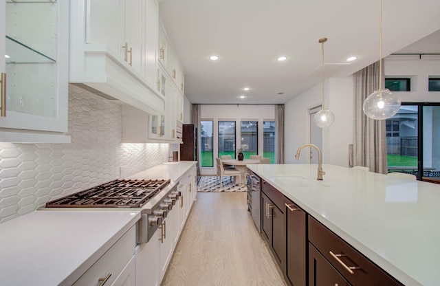 kitchen featuring light hardwood / wood-style flooring, white cabinetry, dark brown cabinets, tasteful backsplash, and pendant lighting