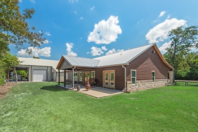 back of property with a yard, ceiling fan, french doors, and a garage