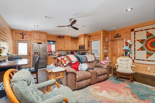 living room with ceiling fan and wooden walls