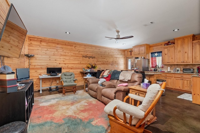 living room with wooden walls, ceiling fan, dark carpet, and visible vents