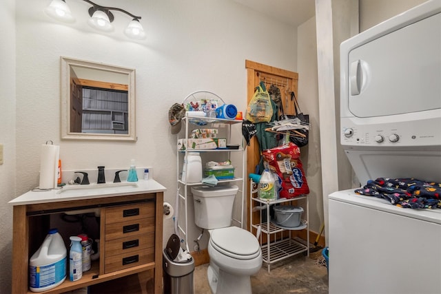 half bathroom featuring vanity, stacked washer and clothes dryer, and toilet