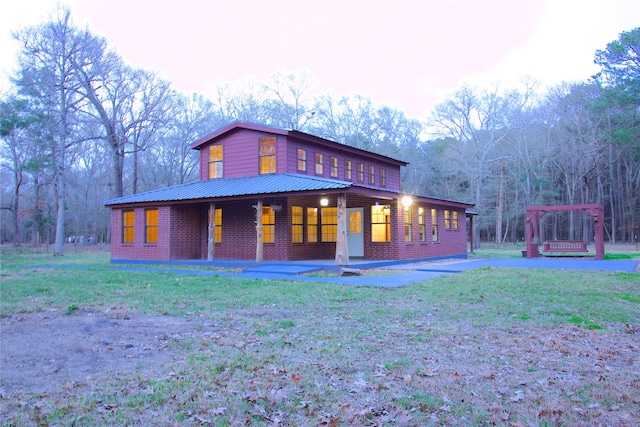 back of property with covered porch and a yard