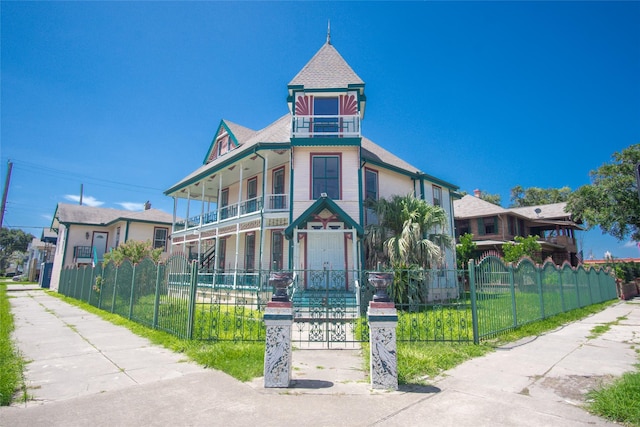 view of front of house with a balcony and a fenced front yard