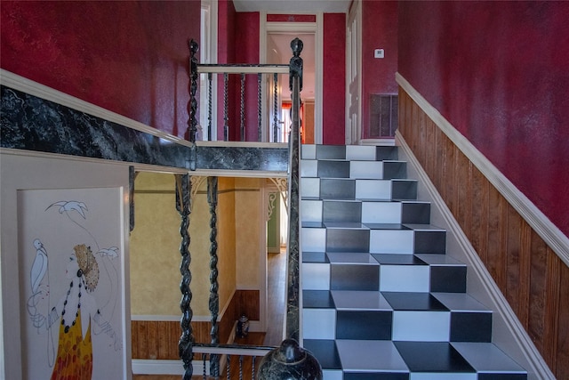 staircase with a wainscoted wall and wood walls