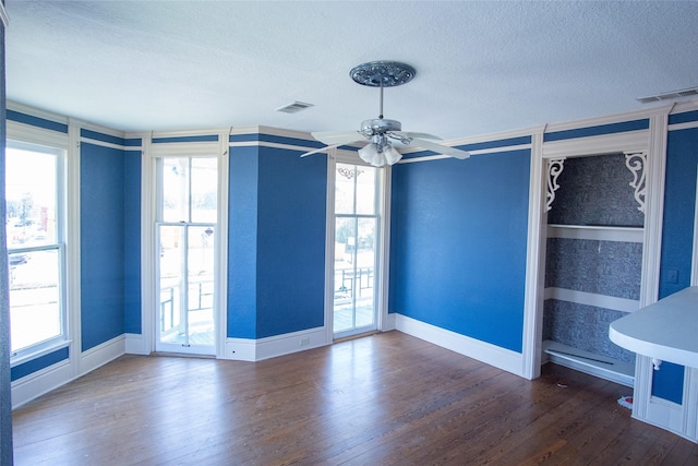 spare room with a textured ceiling, dark wood finished floors, visible vents, and baseboards