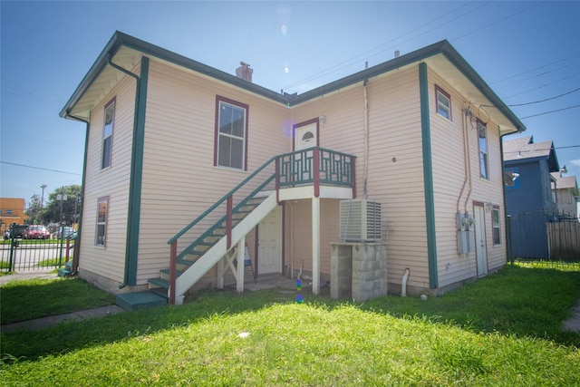 rear view of house with a chimney, stairs, fence, and a yard