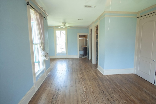 spare room with ceiling fan, wood finished floors, visible vents, baseboards, and crown molding