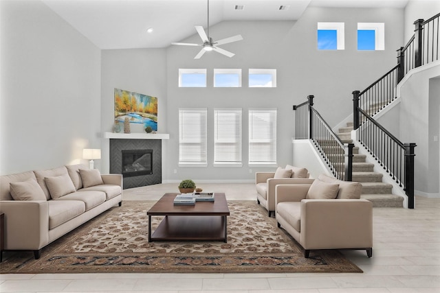 living room featuring ceiling fan, a fireplace, and a high ceiling