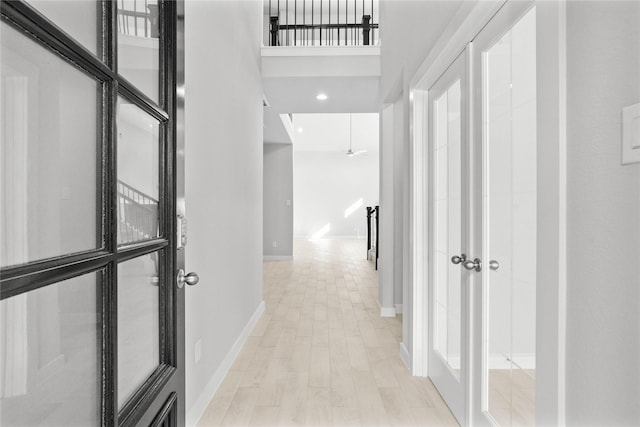 corridor featuring a towering ceiling and light hardwood / wood-style flooring