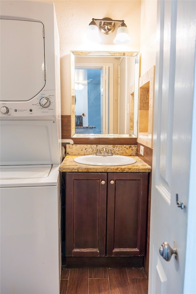 bathroom with stacked washer / dryer, vanity, and wood-type flooring