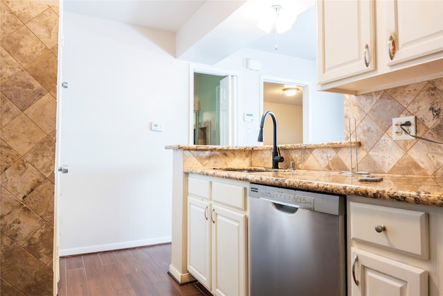 kitchen featuring dark wood-type flooring, decorative backsplash, light stone countertops, stainless steel dishwasher, and white cabinetry