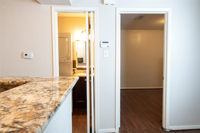 hall with stacked washer and dryer and dark hardwood / wood-style flooring