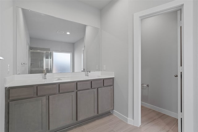 bathroom with wood-type flooring, vanity, and an enclosed shower