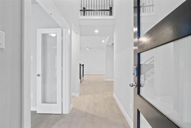 corridor featuring a high ceiling and light wood-type flooring