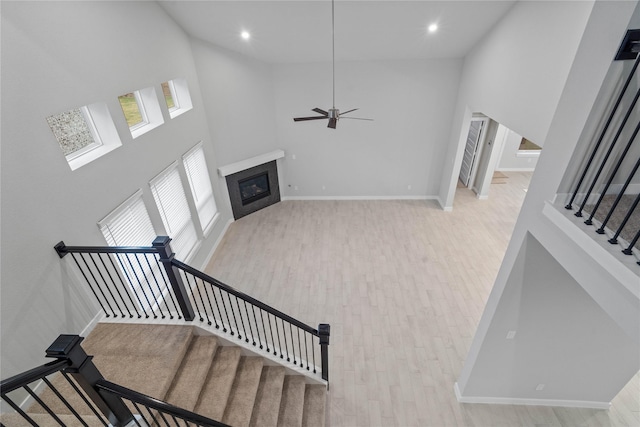 stairs featuring a tiled fireplace, hardwood / wood-style floors, and high vaulted ceiling