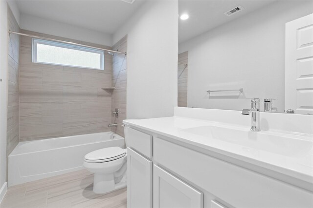 full bathroom with tiled shower / bath, vanity, and toilet