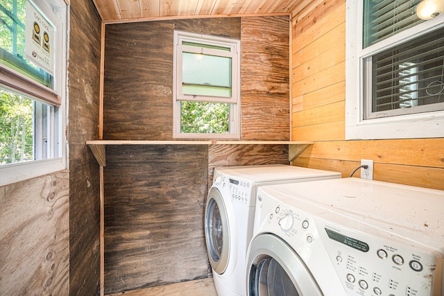 clothes washing area featuring washing machine and clothes dryer, wooden walls, and wooden ceiling