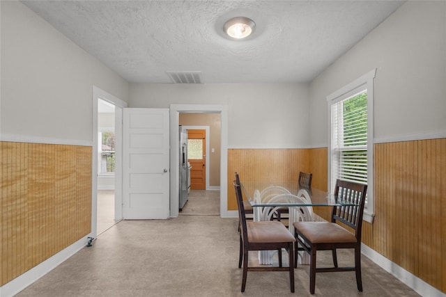 7506 2nd St, Hitchcock, TX 77563 - dining area featuring a textured ceiling, wood walls, visible vents, and wainscoting