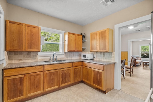 7506 2nd St, Hitchcock, TX 77563 - kitchen with open shelves, a sink, decorative backsplash, white microwave, and visible vents