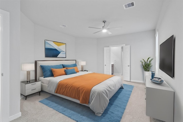 bedroom featuring ceiling fan, light colored carpet, and ensuite bath