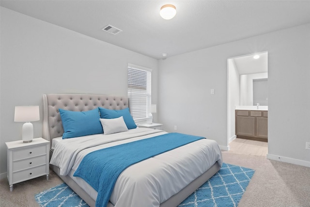 bedroom with ensuite bathroom, carpet flooring, and sink