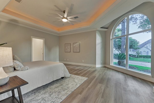 bedroom featuring ceiling fan, a raised ceiling, light hardwood / wood-style floors, and crown molding