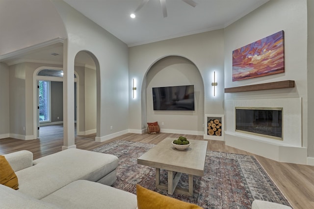 living room with ceiling fan, crown molding, and light hardwood / wood-style floors