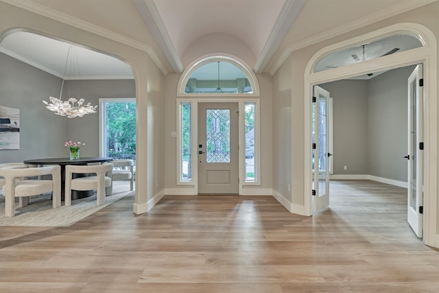 foyer with ornamental molding, an inviting chandelier, and wood-type flooring