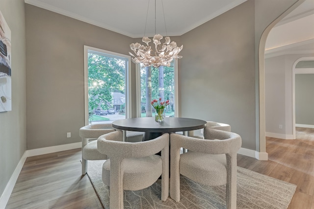 dining room featuring a notable chandelier, light hardwood / wood-style floors, and ornamental molding