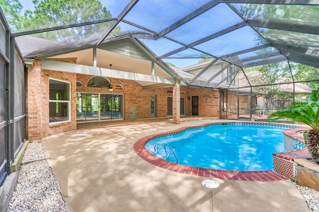 view of pool with ceiling fan, glass enclosure, and a patio area