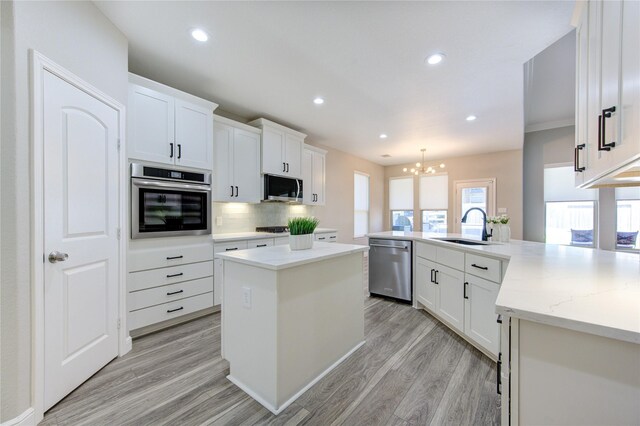 kitchen with light hardwood / wood-style floors, white cabinetry, stainless steel appliances, and a kitchen island