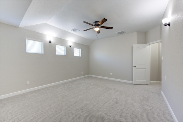 spare room featuring ceiling fan, light carpet, and vaulted ceiling