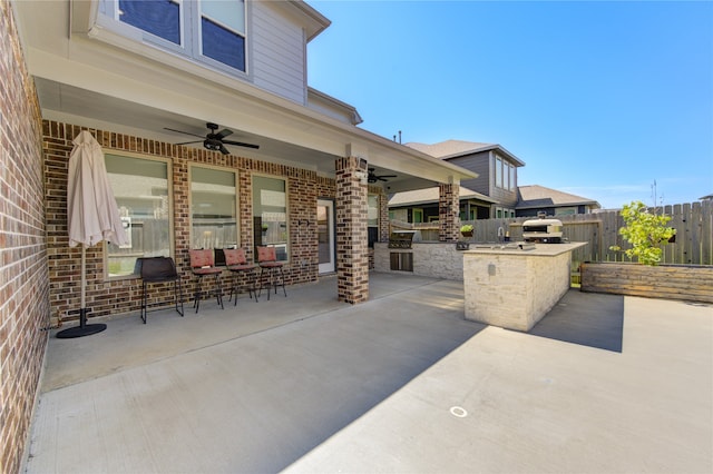 view of patio / terrace featuring ceiling fan, a grill, an outdoor kitchen, and a bar