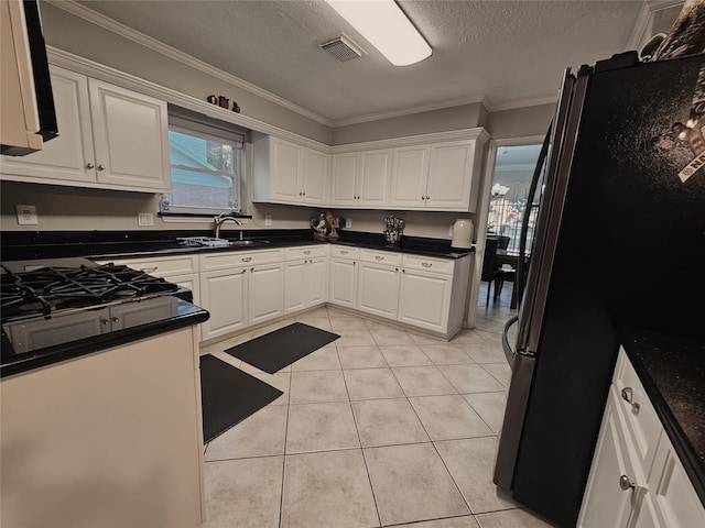 kitchen featuring light tile patterned floors, black refrigerator, and white cabinets