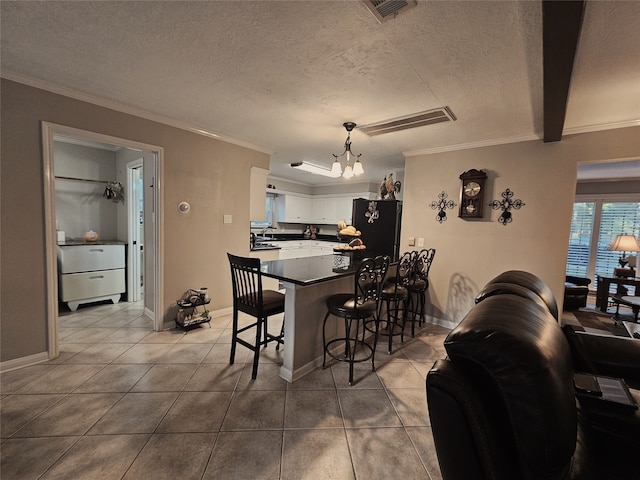 tiled dining space with a textured ceiling, a chandelier, and ornamental molding