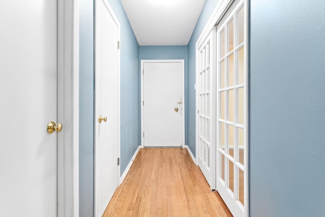 hall featuring a textured ceiling and light hardwood / wood-style flooring