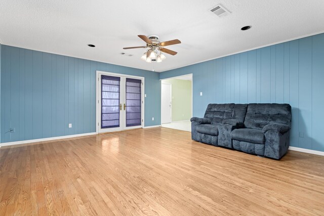 living room featuring ceiling fan, a textured ceiling, french doors, and light hardwood / wood-style floors