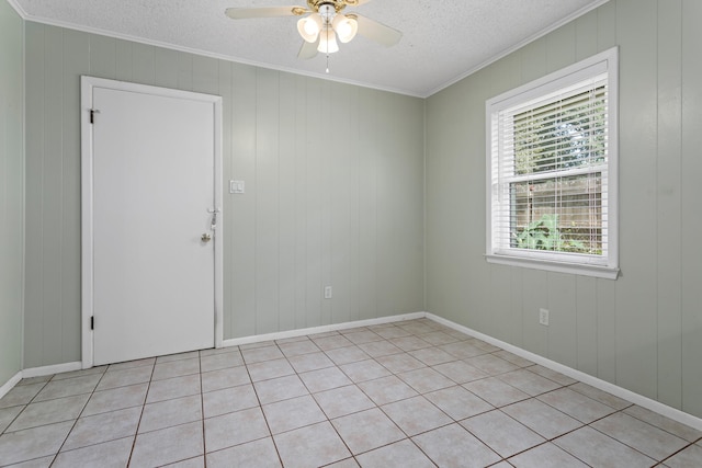 tiled spare room with a textured ceiling, ceiling fan, and crown molding